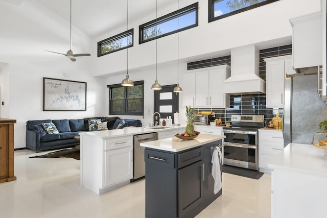 kitchen with a towering ceiling, white cabinets, custom range hood, and stainless steel appliances