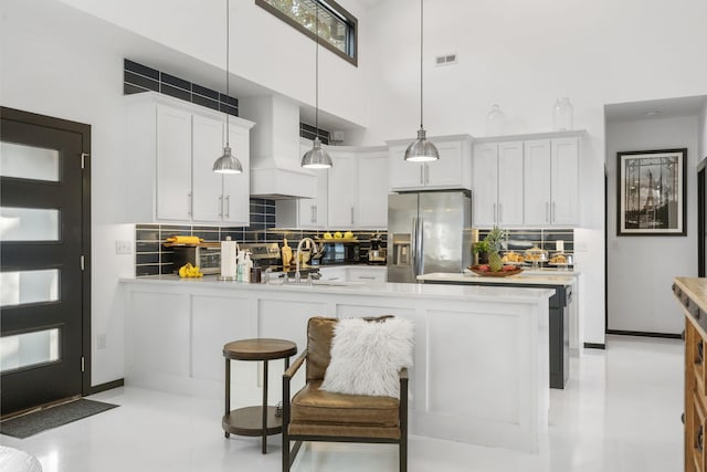 kitchen featuring hanging light fixtures, white cabinetry, decorative backsplash, and stainless steel refrigerator with ice dispenser