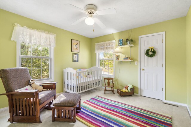 bedroom featuring ceiling fan, carpet flooring, and a nursery area