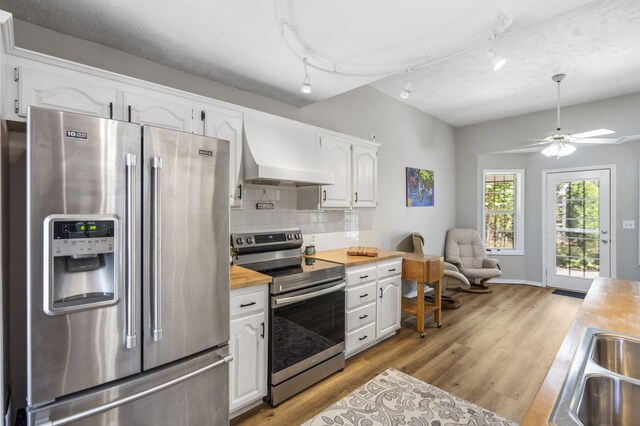 kitchen featuring stainless steel appliances, light hardwood / wood-style floors, wood counters, white cabinetry, and premium range hood