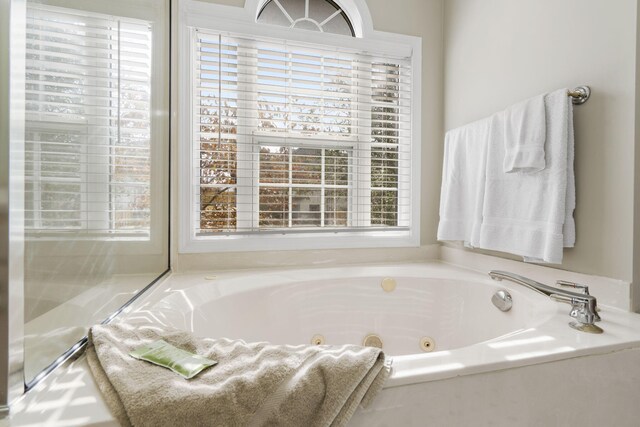 bathroom with a relaxing tiled tub and a wealth of natural light