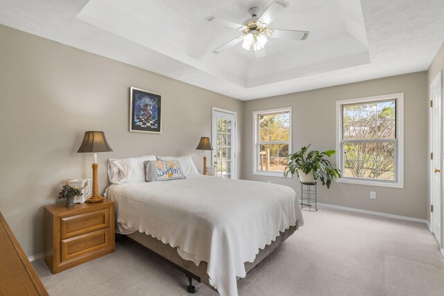 carpeted bedroom with a tray ceiling and ceiling fan