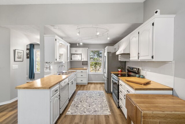 kitchen featuring white cabinets, decorative backsplash, sink, light hardwood / wood-style flooring, and white appliances