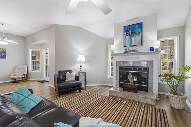 living room featuring vaulted ceiling, hardwood / wood-style flooring, ceiling fan, and a high end fireplace