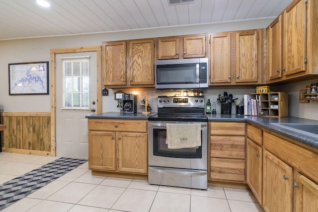 kitchen with stainless steel appliances, light tile patterned flooring, wood ceiling, and crown molding