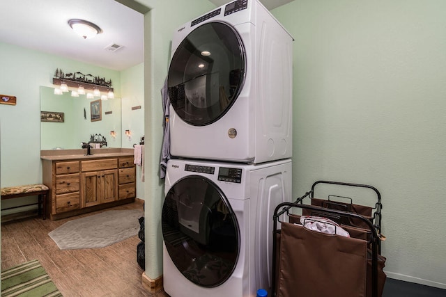 clothes washing area with light hardwood / wood-style floors and stacked washer and clothes dryer