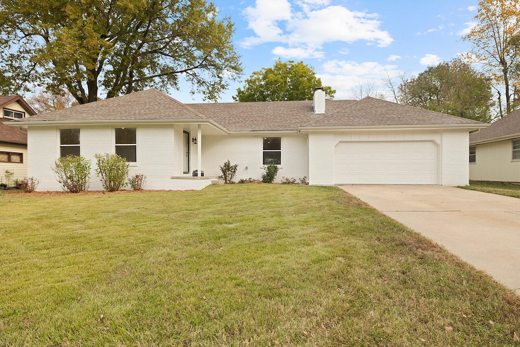 ranch-style house with a garage and a front lawn