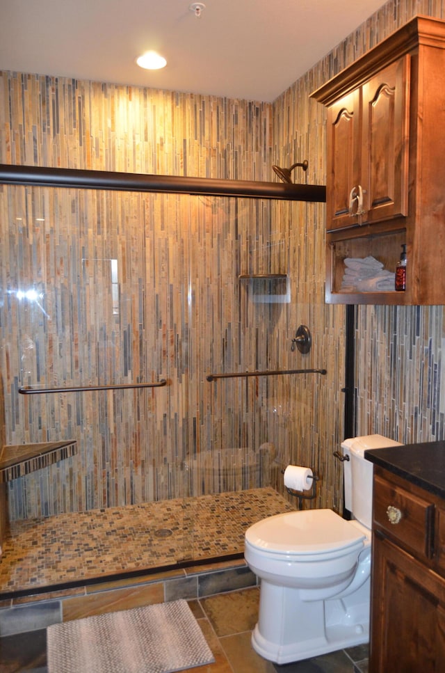 bathroom featuring toilet, tile patterned flooring, wood walls, vanity, and a shower