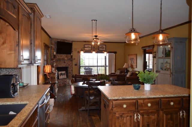 kitchen with a fireplace, hanging light fixtures, dark hardwood / wood-style flooring, a center island, and dishwasher