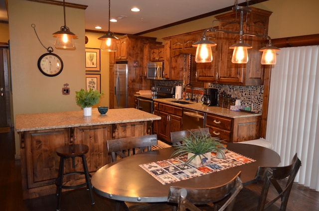 kitchen with hanging light fixtures, sink, backsplash, and appliances with stainless steel finishes