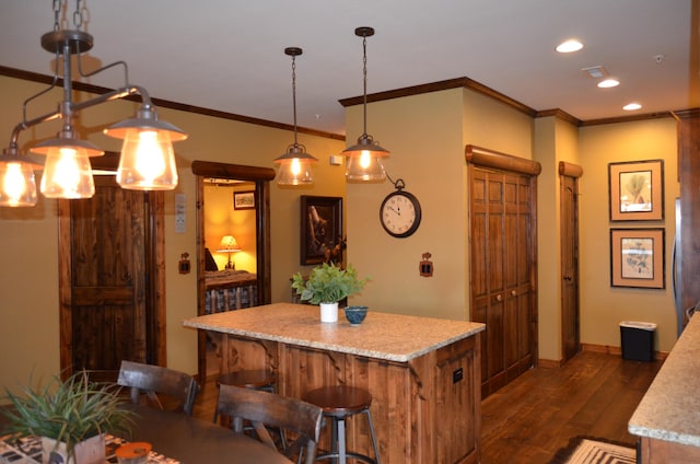 kitchen with ornamental molding, a breakfast bar area, decorative light fixtures, a center island, and dark wood-type flooring