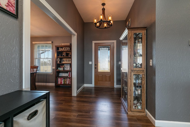 foyer entrance with dark wood-type flooring, a chandelier, and lofted ceiling