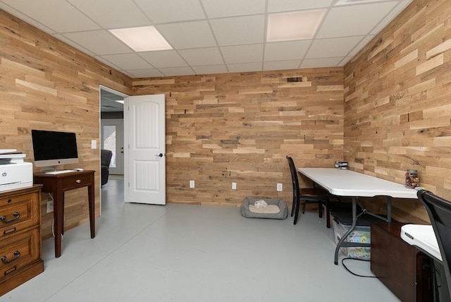 office featuring wood walls, concrete floors, and a drop ceiling