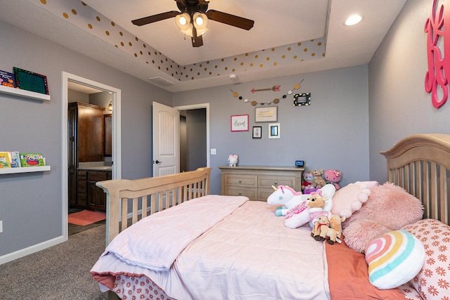 carpeted bedroom with ceiling fan, ensuite bath, and a tray ceiling