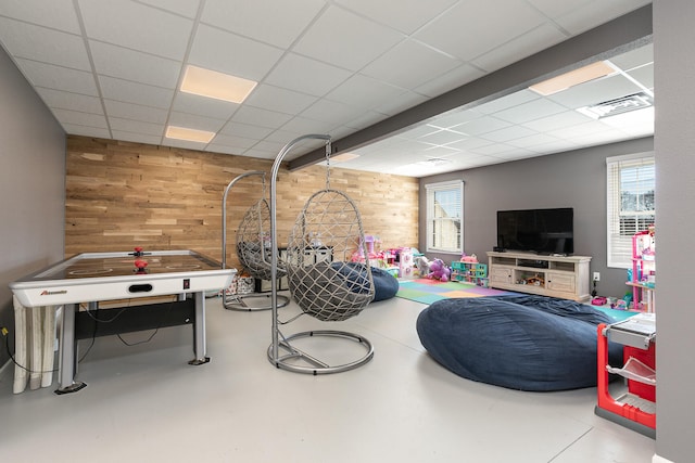 playroom featuring wood walls and a paneled ceiling