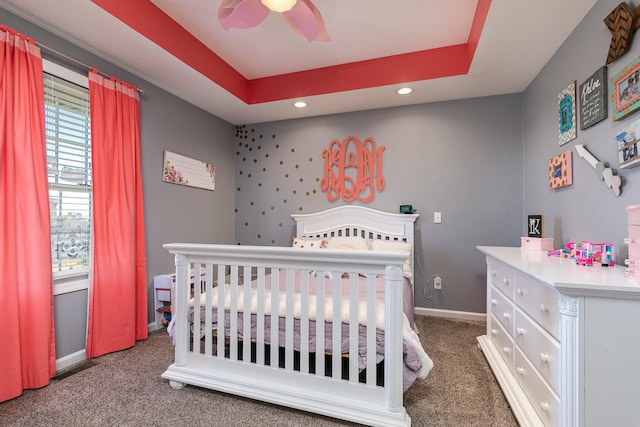 carpeted bedroom featuring ceiling fan and a raised ceiling