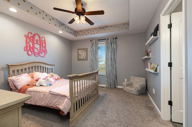 bedroom featuring ceiling fan, carpet, and a tray ceiling