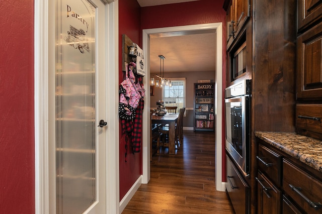 corridor featuring an inviting chandelier and dark hardwood / wood-style flooring