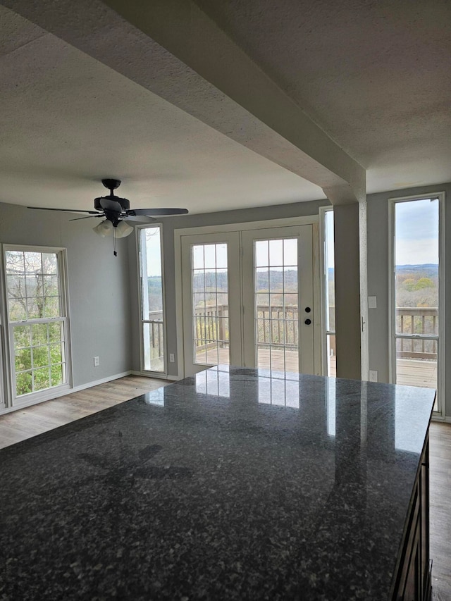 empty room featuring a textured ceiling, hardwood / wood-style floors, a healthy amount of sunlight, and ceiling fan