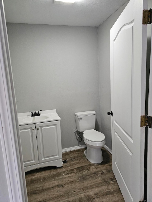 bathroom featuring toilet, vanity, and hardwood / wood-style floors