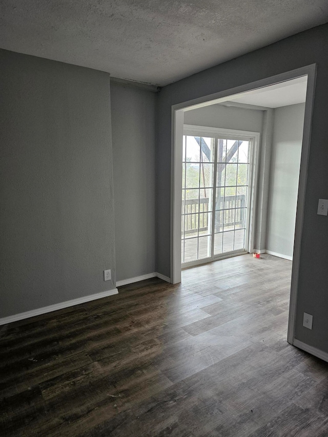 unfurnished room with a textured ceiling and dark hardwood / wood-style flooring