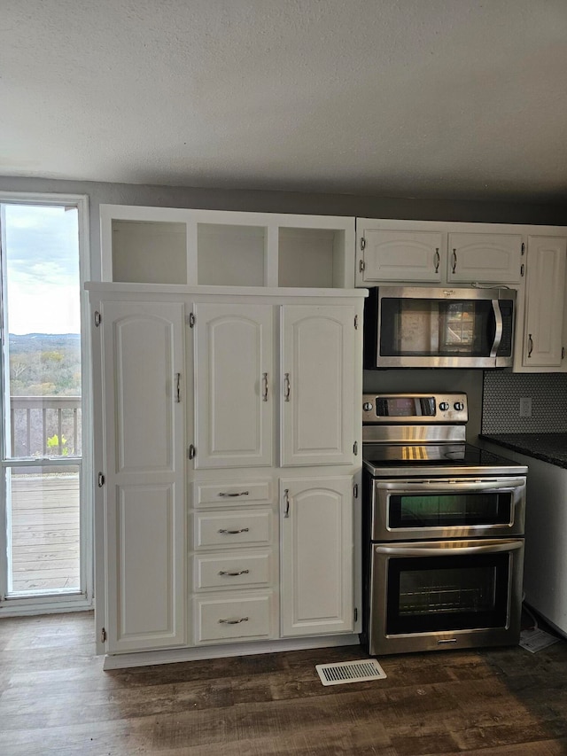 kitchen with white cabinets, appliances with stainless steel finishes, and dark hardwood / wood-style floors