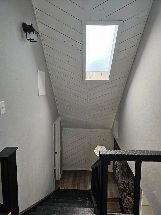 staircase featuring wood walls, wood-type flooring, and vaulted ceiling