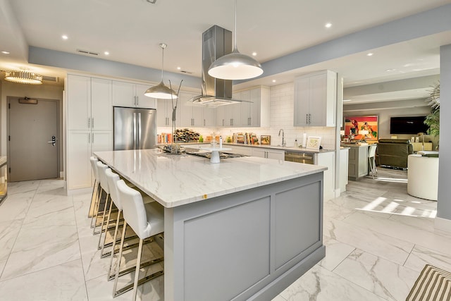 kitchen featuring island range hood, stainless steel appliances, a large island with sink, pendant lighting, and white cabinets