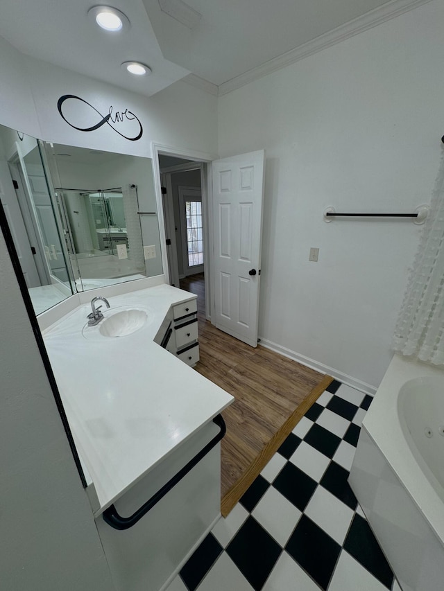 bathroom featuring a tub to relax in, vanity, hardwood / wood-style floors, and ornamental molding