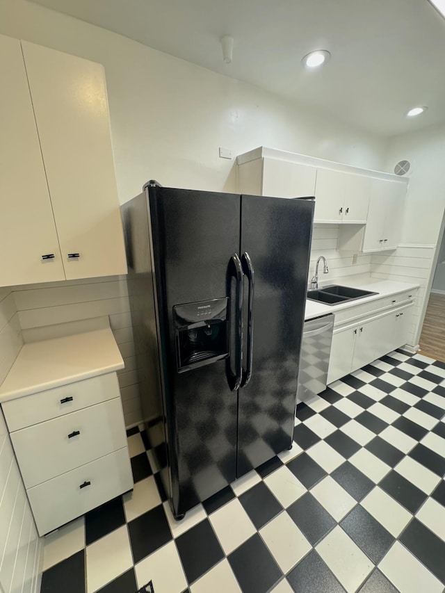 kitchen featuring black fridge, sink, backsplash, stainless steel dishwasher, and white cabinets