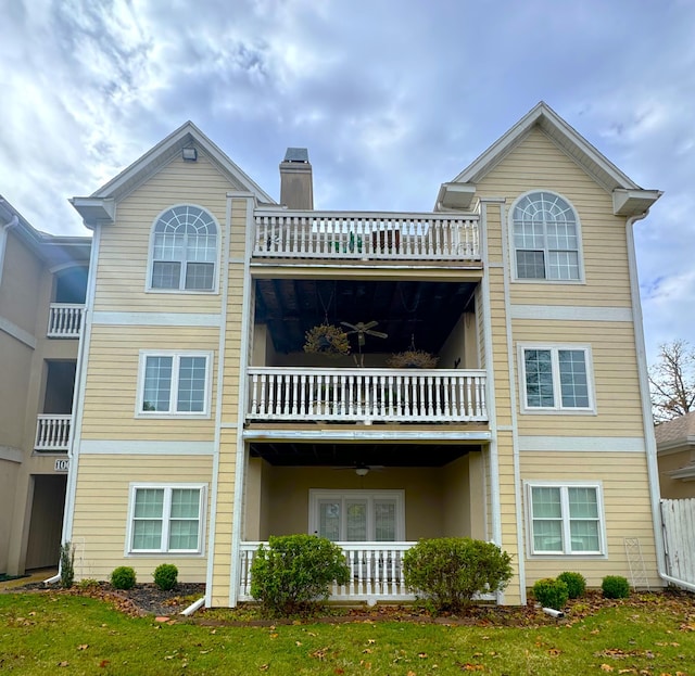 back of property featuring a lawn, ceiling fan, and a balcony