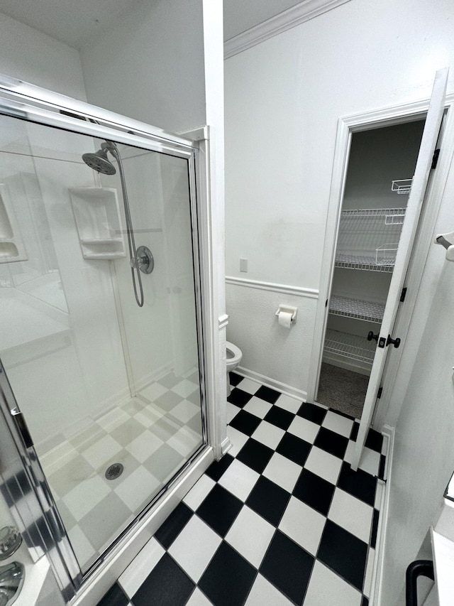 bathroom with a shower with shower door, toilet, and crown molding