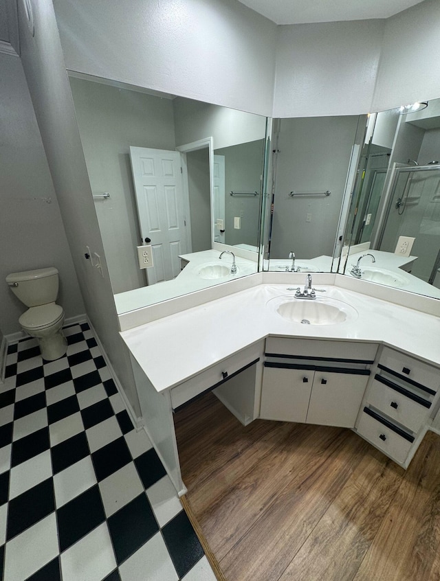 bathroom with an enclosed shower, wood-type flooring, toilet, and vanity