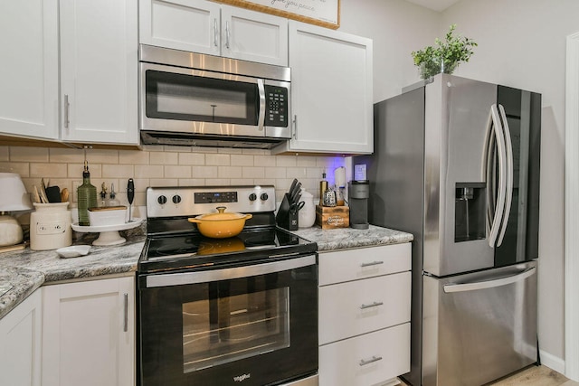 kitchen with light stone countertops, white cabinetry, and appliances with stainless steel finishes