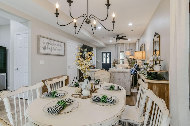 dining room with hardwood / wood-style floors and ceiling fan with notable chandelier