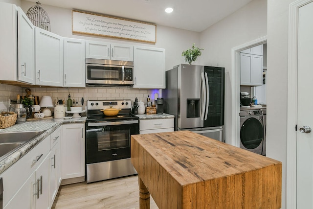 kitchen with backsplash, white cabinetry, light wood-type flooring, and appliances with stainless steel finishes