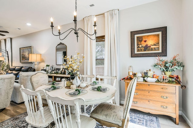 dining space with wood-type flooring and ceiling fan with notable chandelier