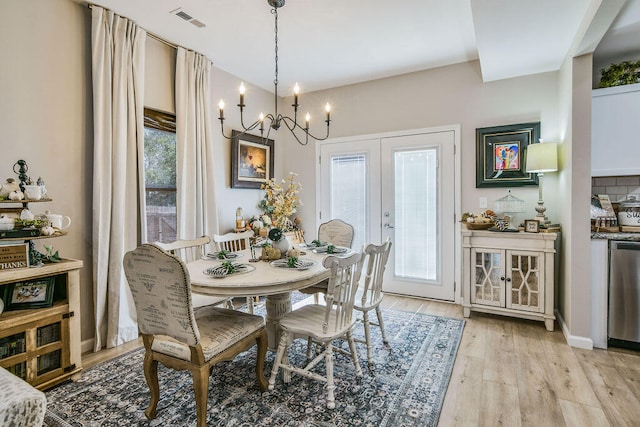 dining space featuring an inviting chandelier, plenty of natural light, light wood-type flooring, and french doors