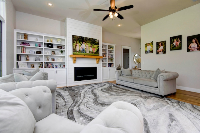 living room featuring hardwood / wood-style flooring, ceiling fan, and a fireplace