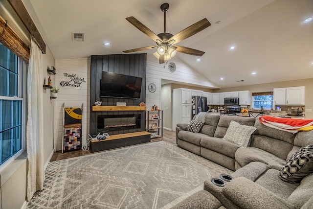 living room with wood walls, hardwood / wood-style flooring, ceiling fan, and vaulted ceiling