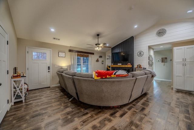 living room with lofted ceiling, wooden walls, dark hardwood / wood-style floors, and ceiling fan