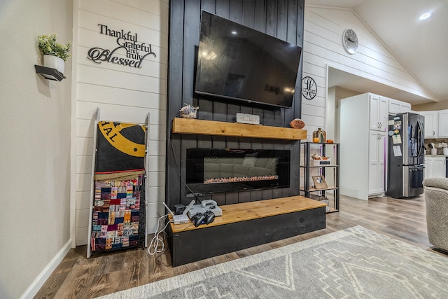 living room with wood-type flooring, wooden walls, and lofted ceiling