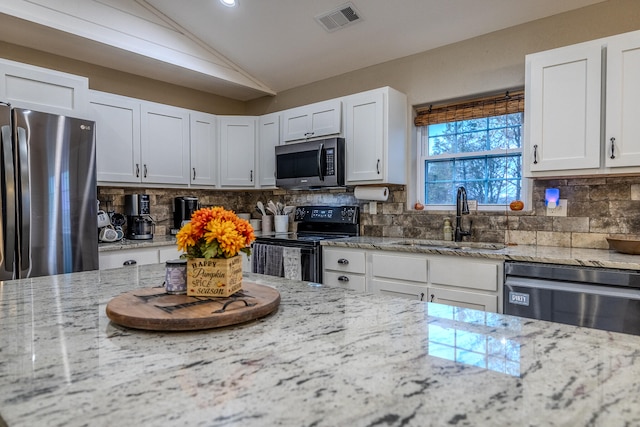 kitchen with white cabinetry, appliances with stainless steel finishes, sink, and vaulted ceiling