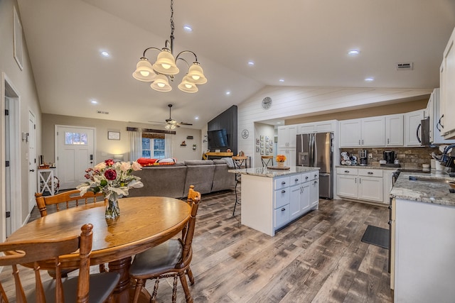 kitchen with white cabinets, lofted ceiling, hanging light fixtures, and stainless steel appliances