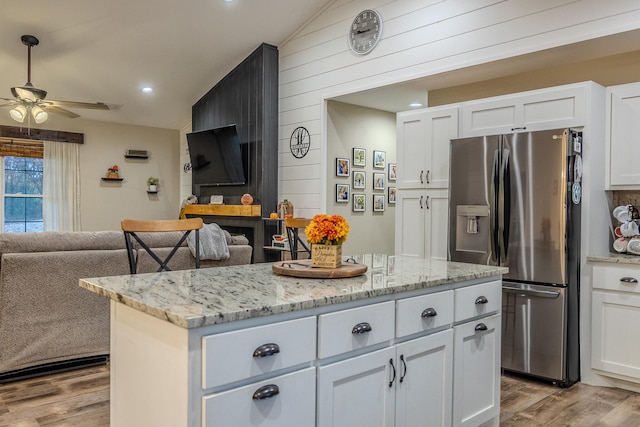 kitchen with white cabinets, lofted ceiling, and stainless steel fridge with ice dispenser