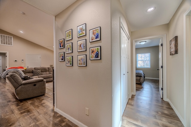 corridor featuring wood-type flooring and vaulted ceiling