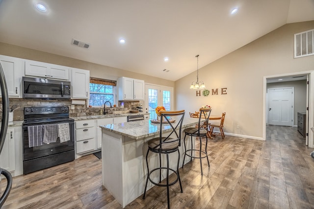 kitchen with stainless steel appliances, light wood-type flooring, white cabinetry, pendant lighting, and a center island