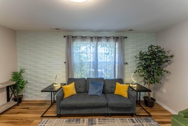 living room with brick wall and light hardwood / wood-style flooring