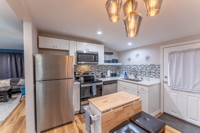 kitchen featuring sink, white cabinetry, appliances with stainless steel finishes, and decorative light fixtures