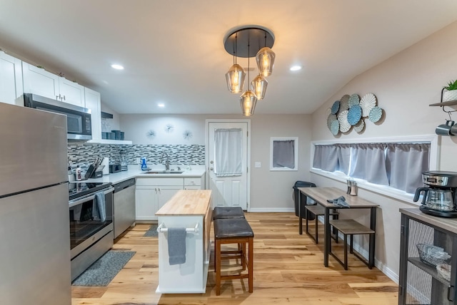 kitchen featuring light hardwood / wood-style floors, sink, appliances with stainless steel finishes, decorative light fixtures, and white cabinets